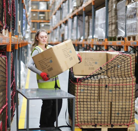 Warehouse operator loading cartons into a pallet secured with a reusable pallet cargo net