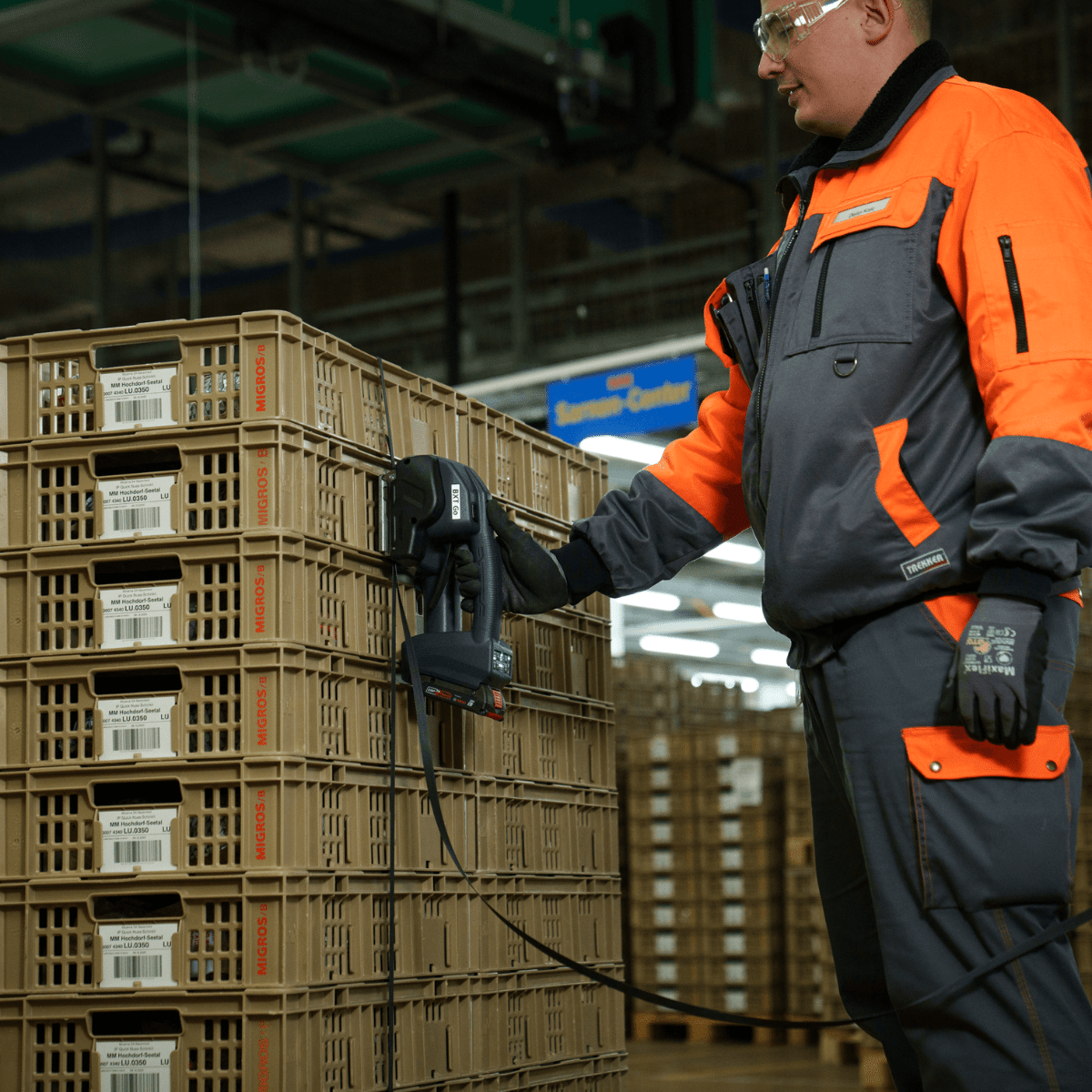 BXT Go Battery Powered Strapping Tool in Use | Maxpack Worker using a BXT Go battery powered strapping tool to secure stacked crates in a warehouse.